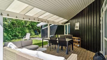 Een buitenpatio met een bank, eettafel, stoelen en een klein rond tafeltje.