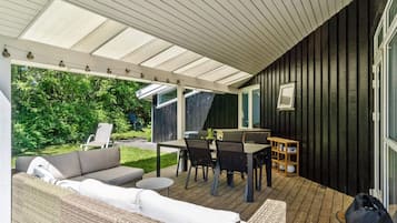 Un espacio al aire libre techado con un sofá, una mesa de comedor y sillas.