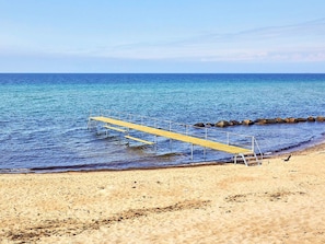 A beach with a wooden pier extending into the sea, surrounded by rocks and sandy shore. - 5 Star Holiday Home in Graested (Graested)