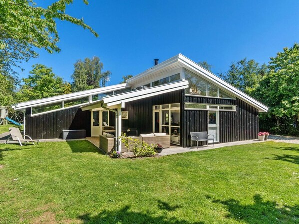 A modern house with a covered patio, a small garden, and a clear blue sky.