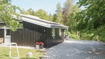 A single-story building with a dark exterior, a gravel driveway, and a small garden area with potted plants.