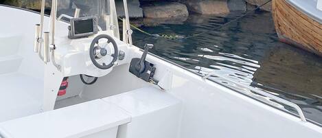 A boat's interior with a steering wheel, control panel, and seating area.