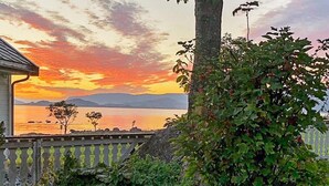 A coastal view with a sunset, a white fence, and greenery. - 4 Star Holiday Home in Svelgen (Bremanger)