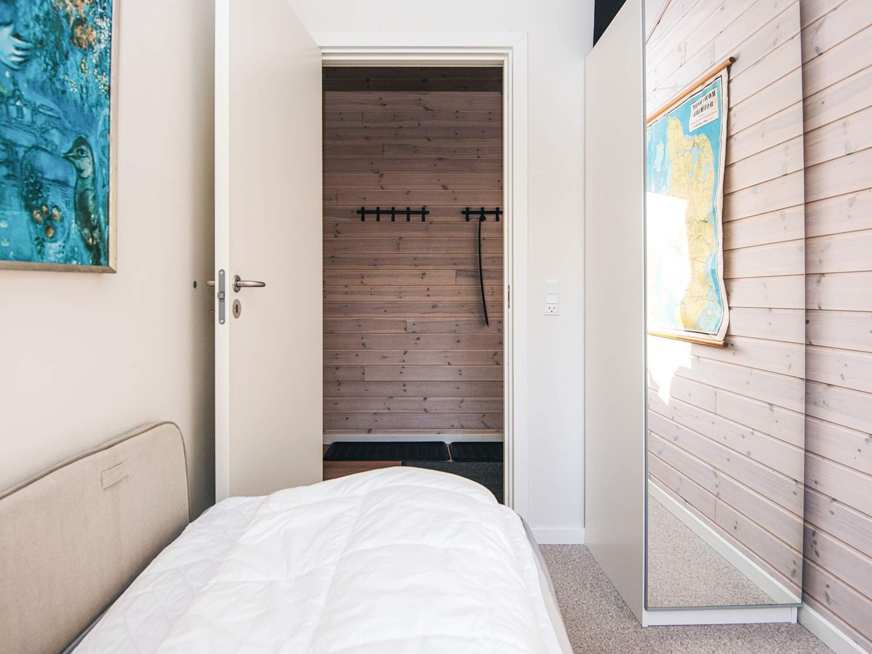 Quarto com cama, guarda-roupa de madeira e um mapa na parede.