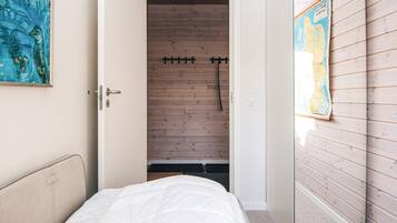 A bedroom with a bed, a wooden wardrobe, and a map on the wall.