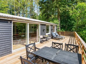 A wooden deck with outdoor furniture, a glass door entrance, and a view of a forested area. - 4 Star Holiday Home in Ans By (Ans)
