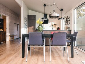 A modern kitchen with a dining area, featuring a wooden floor, a central island, and pendant lighting. - 4 Star Holiday Home in Ans By (Ans)