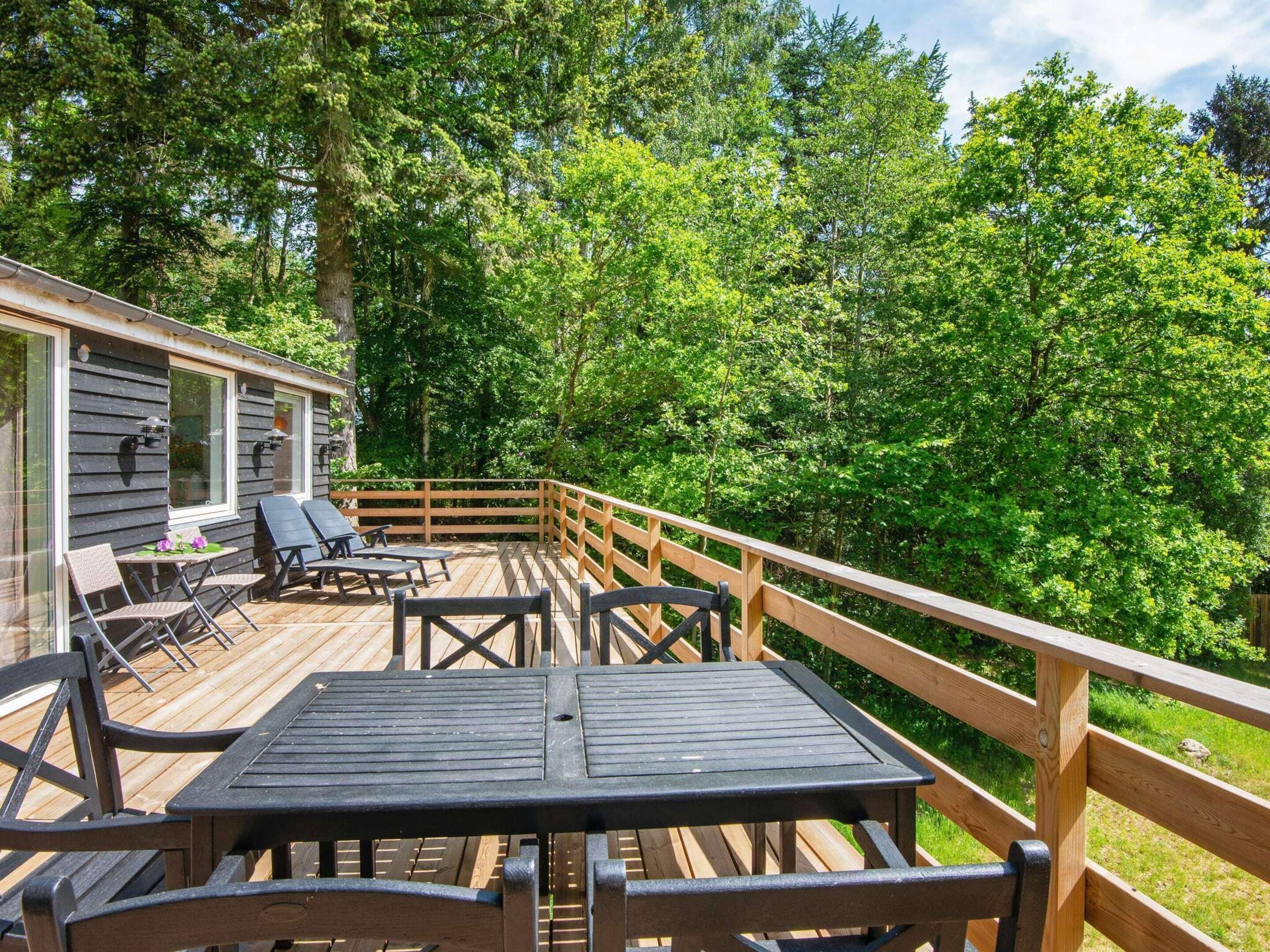 A wooden deck with outdoor furniture, surrounded by dense trees.