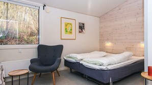A small, modern room with a bed, a chair, and a window overlooking a forest. - 4 Star Holiday Home in Ans By (Ans)