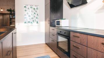 A modern kitchen with wooden cabinets, a built-in oven, and a microwave.
