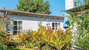 A white house with a tiled roof, a garden with ferns, and a clear blue sky.