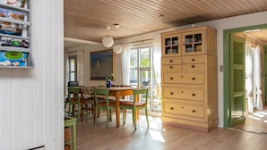 A dining area with a wooden table and chairs, a cabinet with multiple drawers, and a painting on the wall.