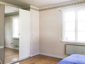 A bedroom with a wooden floor, a radiator, a window, and a door. - 5 Star Holiday Home in Asbro (Asbro)