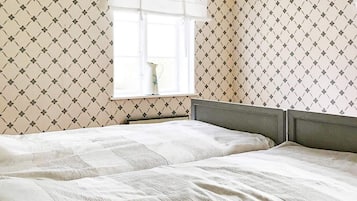 Una habitación con dos camas, una ventana con vistas y papel tapiz estampado.
