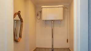 Une salle de bain avec des toilettes blanches, un meuble-lavabo en bois et un miroir doté d’un cadre orné.
