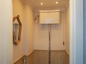 A bathroom with a white toilet, a wooden vanity, and a mirror with an ornate frame. - 5 Star Holiday Home in Asbro (Asbro)