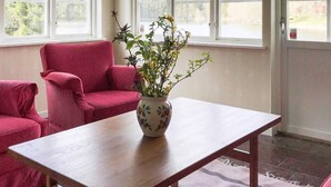 A room with a wooden table, a red chair, and a vase with a plant. - 5 Star Holiday Home in Asbro (Asbro)
