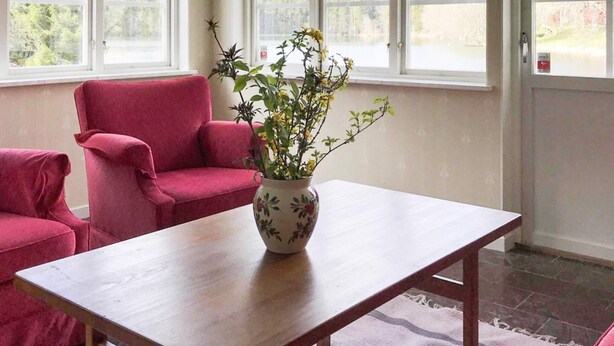 Une pièce avec une table en bois, une chaise rouge et un vase avec une plante.