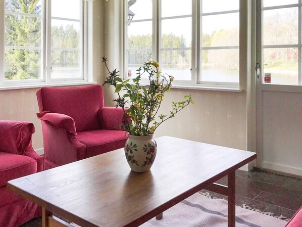 A room with a wooden table, a red chair, and a vase with a plant. - 5 Star Holiday Home in Asbro (Asbro)