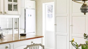 A kitchen with white cabinets, a refrigerator, a dining table with a checkered tablecloth, and a vase with flowers. - 5 Star Holiday Home in Asbro (Asbro)
