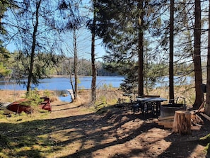 A campsite with a table and chairs, a red canoe, and a wooden bench. - 5 Star Holiday Home in Asbro (Asbro)