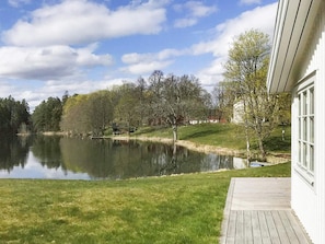A lakeside view with a wooden deck, a building with large windows, and a grassy area. - 5 Star Holiday Home in Asbro (Asbro)