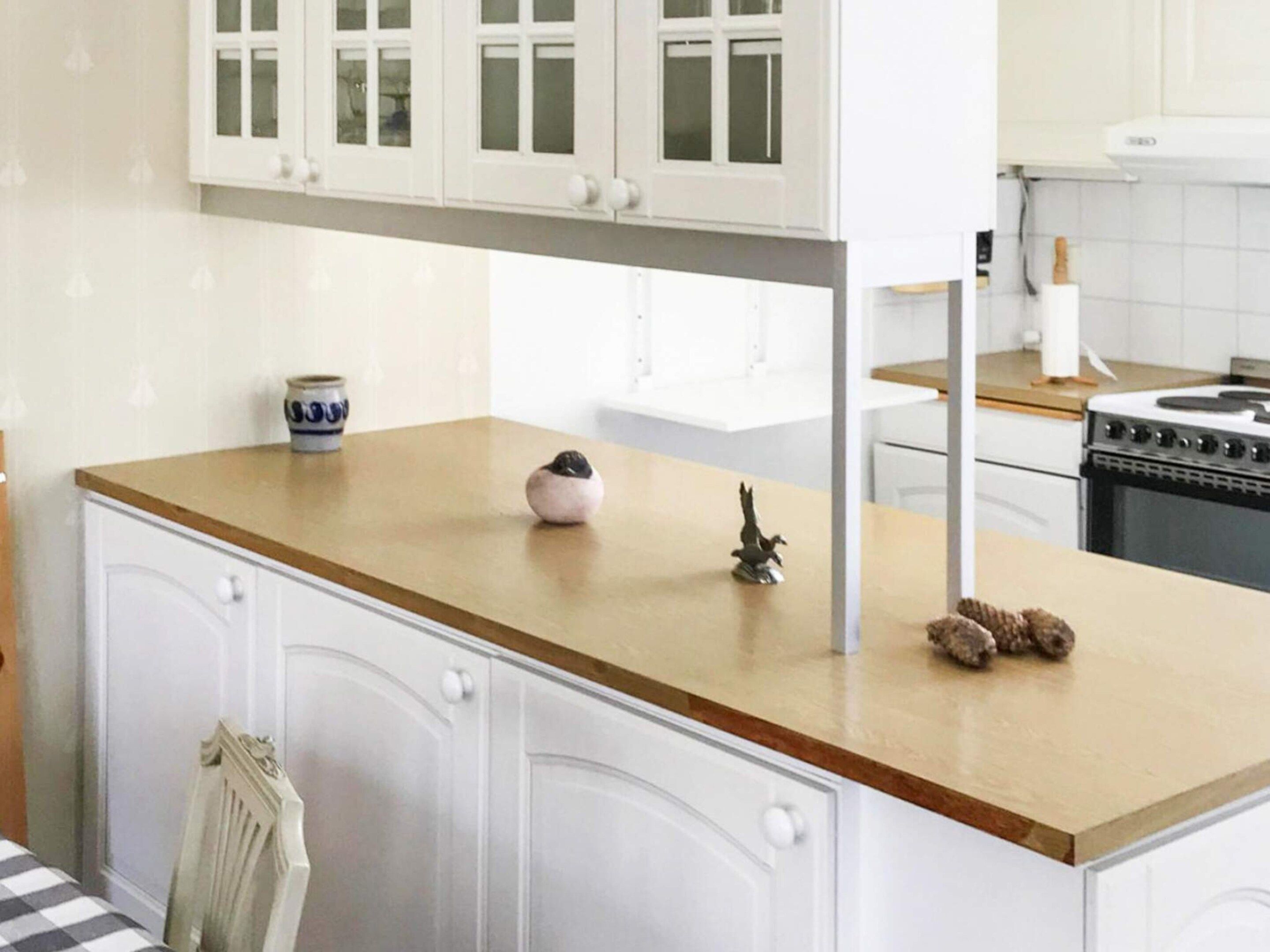 A kitchen with white cabinets, a wooden countertop, a stove, and a sink.