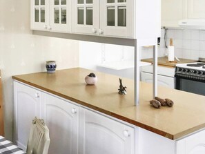 A kitchen with white cabinets, a wooden countertop, a stove, and a sink. - 5 Star Holiday Home in Asbro (Asbro)
