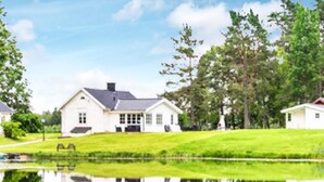 A large white house with a pond in front, surrounded by trees and grass. - 5 Star Holiday Home in Asbro (Asbro)