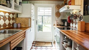 A compact kitchen with a checkered floor, wooden countertops, and a white door leading outside. - 8 Person Holiday Home in Hurup Thy-by Traum (Hurup Thy)