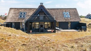 Ett hus med halmtak, en balkong, en liten veranda och en flagga.