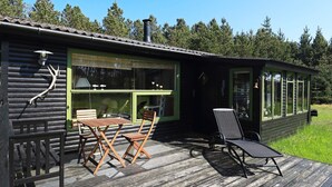 Een houten hut met een terras, een tafel en twee stoelen.