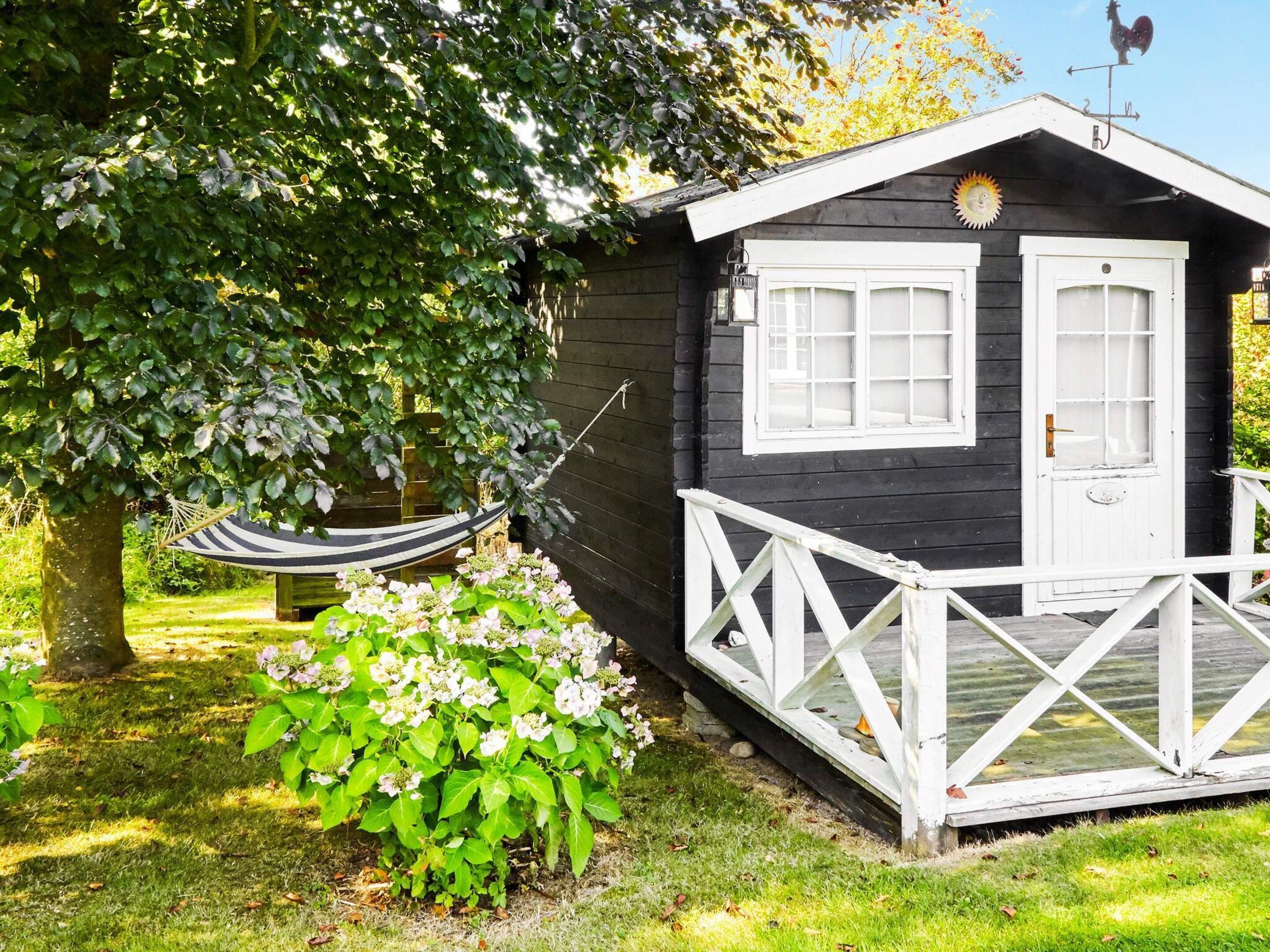 A small cabin with a white porch and a hammock.