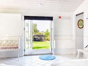 A room with a bed, a bench, a blue mat, and a door leading to a garden. - 4 Star Holiday Home in Nykobing Sj (Nykobing Sjaelland)