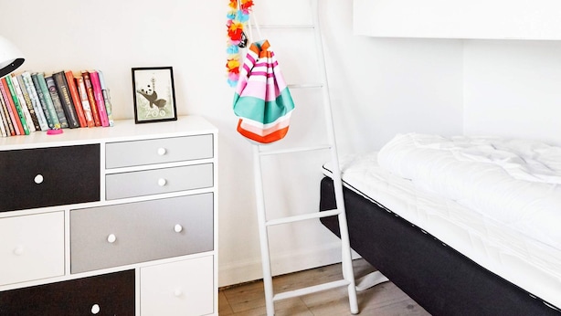 A bunk bed with a white mattress, a white dresser with multiple drawers, a ladder, and a bookshelf with books and a framed picture. - 4 Star Holiday Home in Nykobing Sj (Nykobing Sjaelland)
