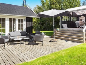 Una terraza con mobiliario exterior, una zona cubierta y una escalera que conduce a un porche cubierto.