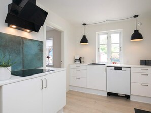 A modern kitchen with white cabinetry, a black countertop, and pendant lighting. - 4 Star Holiday Home in Lokken (Lokken)