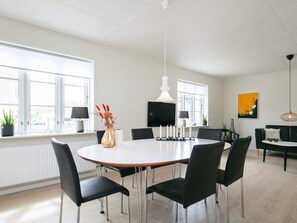 Una sala da pranzo moderna con un tavolo rotondo, sedie nere e un soffitto bianco.