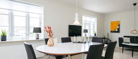 Een moderne eetruimte met een ronde tafel, zwarte stoelen en een wit plafond.
