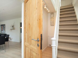 A wooden door with a modern handle, a staircase with beige carpet, and a white radiator on the wall.