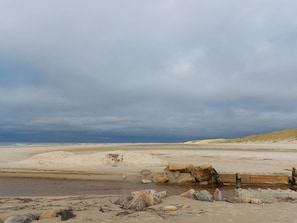 Una spiaggia con una recinzione di legno e rocce in primo piano.