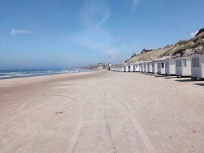 A beach with a row of white mobile homes along the shore. - 4 Star Holiday Home in Lokken (Lokken)