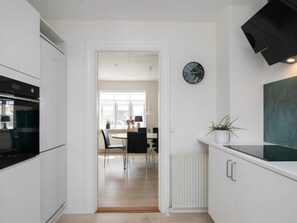 Una cocina moderna con armarios blancos, un reloj negro y una planta en maceta sobre la encimera.