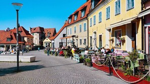 A cobblestone street lined with traditional European buildings, outdoor seating areas, and a clear blue sky. - 6 Person Holiday Home in Visby-by Traum (Visby)
