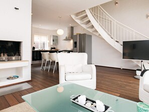 A modern living room with a glass coffee table, white sofas, a fireplace, and a staircase leading to an upper level. - 4 Star Holiday Home in Skagen (Skagen)