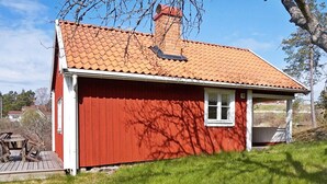 A red wooden house with a tiled roof, a window, and a porch. - 6 Person Holiday Home in Vaxholm (Vaxholm)