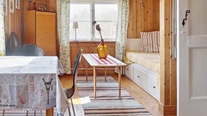 A cozy room with a wooden floor, a bed with striped bedding, a table with a vase, and a chair. - 6 Person Holiday Home in Vaxholm (Vaxholm)