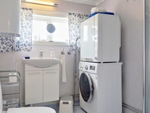 Une petite salle de bain comprenant un lavabo, un miroir, ainsi qu’un lave-linge et un sèche-linge superposés.