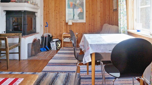 A cozy room with a bed, a table, a chair, a fireplace, and a window with curtains. - 6 Person Holiday Home in Vaxholm (Vaxholm)