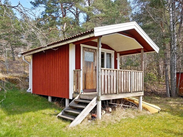 Une petite cabane avec une véranda, des marches en bois et une porte.